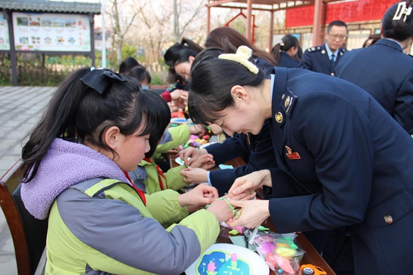 近日，在四川省遂寧市安居區金雞村兒童之家，重慶市潼南區稅務局和四川省遂寧市稅務局30余名女性職工，為小朋友系上親手制作的手串?？秭z